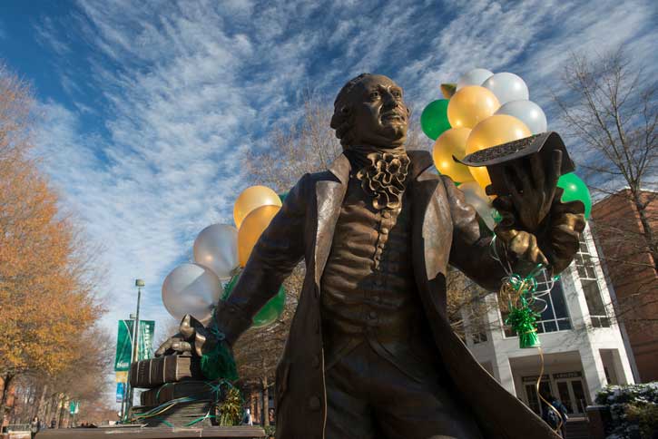 Statue of George Mason with gold and green balloons on Mason Fairfax Campus